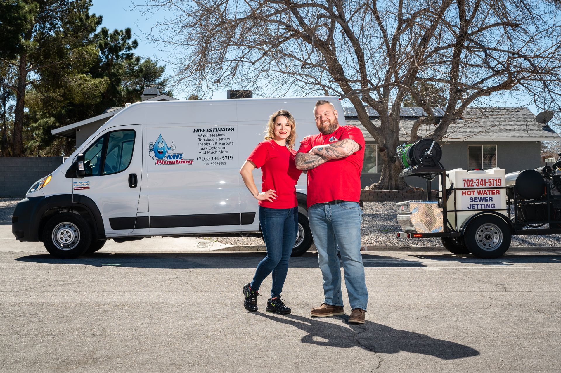 The MC Plumbing crew in red shirts beside the van and hot-water sewer-jetting trailer.