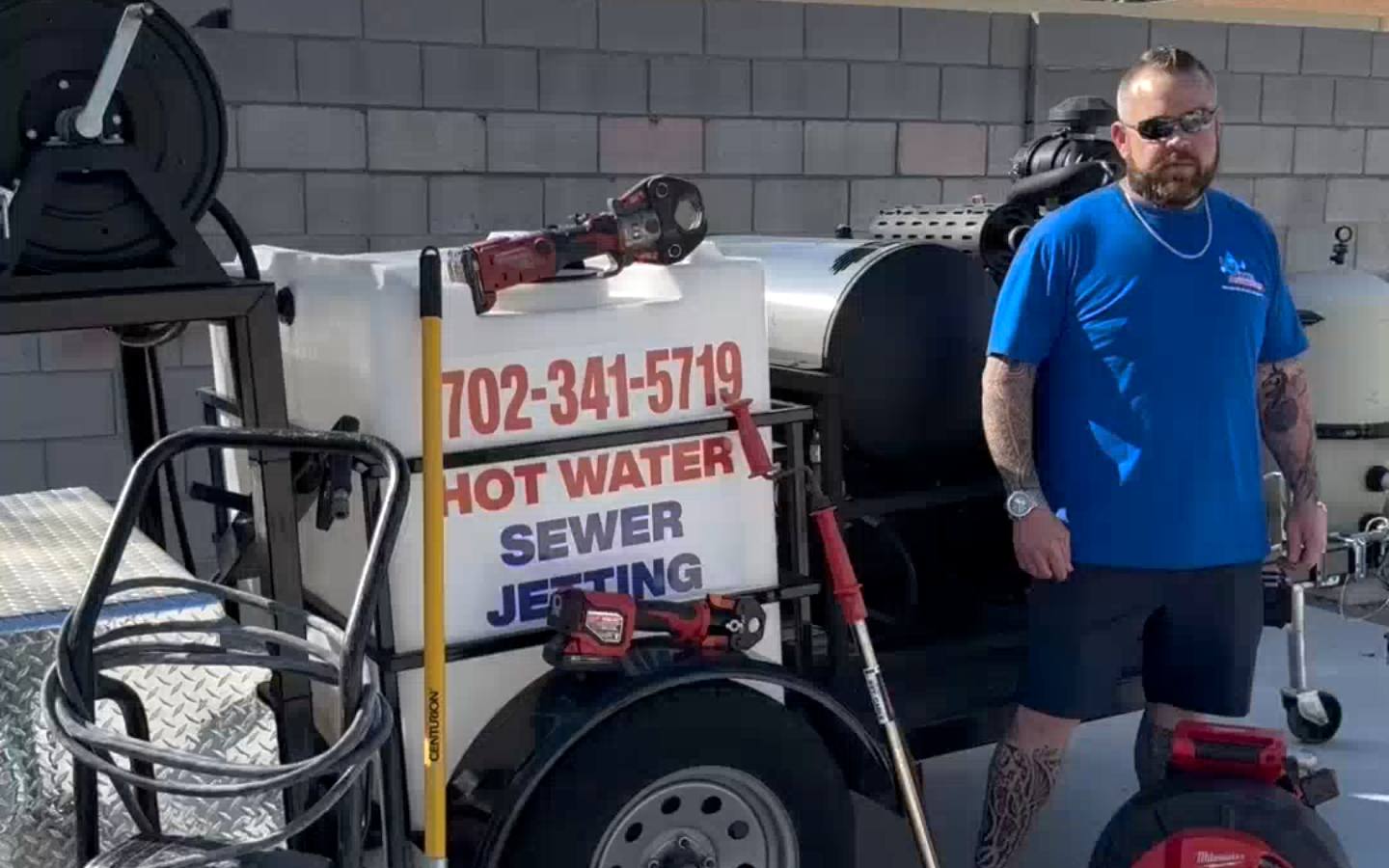 An MC Plumbing crew member beside the hot-water sewer-jetting trailer.
